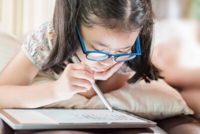 Young child in glasses looking closely at a smart device
